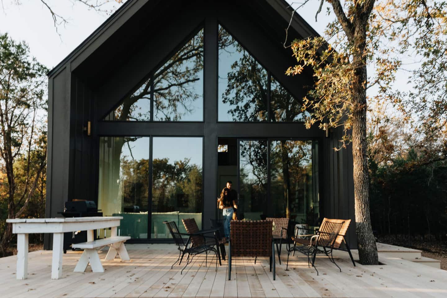 The Four Winds cabin, a modern black A-frame with a glass gable, at dusk on the deck
